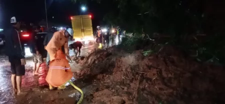 Petugas menangani material longsor di Garut yang menghalangi jalan raya